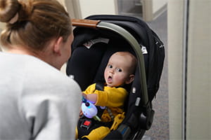 A woman looks at a baby in a car seat