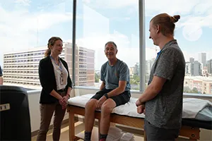 Physical therapists with patient in Denver Health physical therapy gym.