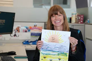 Charlotte Olsen holds up a picture while sitting at her desk