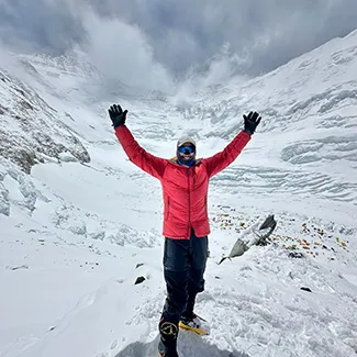 Denver Health patient Rich Draves standing on Mount Everest with his arms raised in the air.