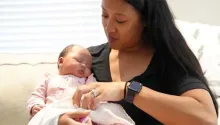 A new mother comforts her newborn baby at home during a visit from Family Connects.